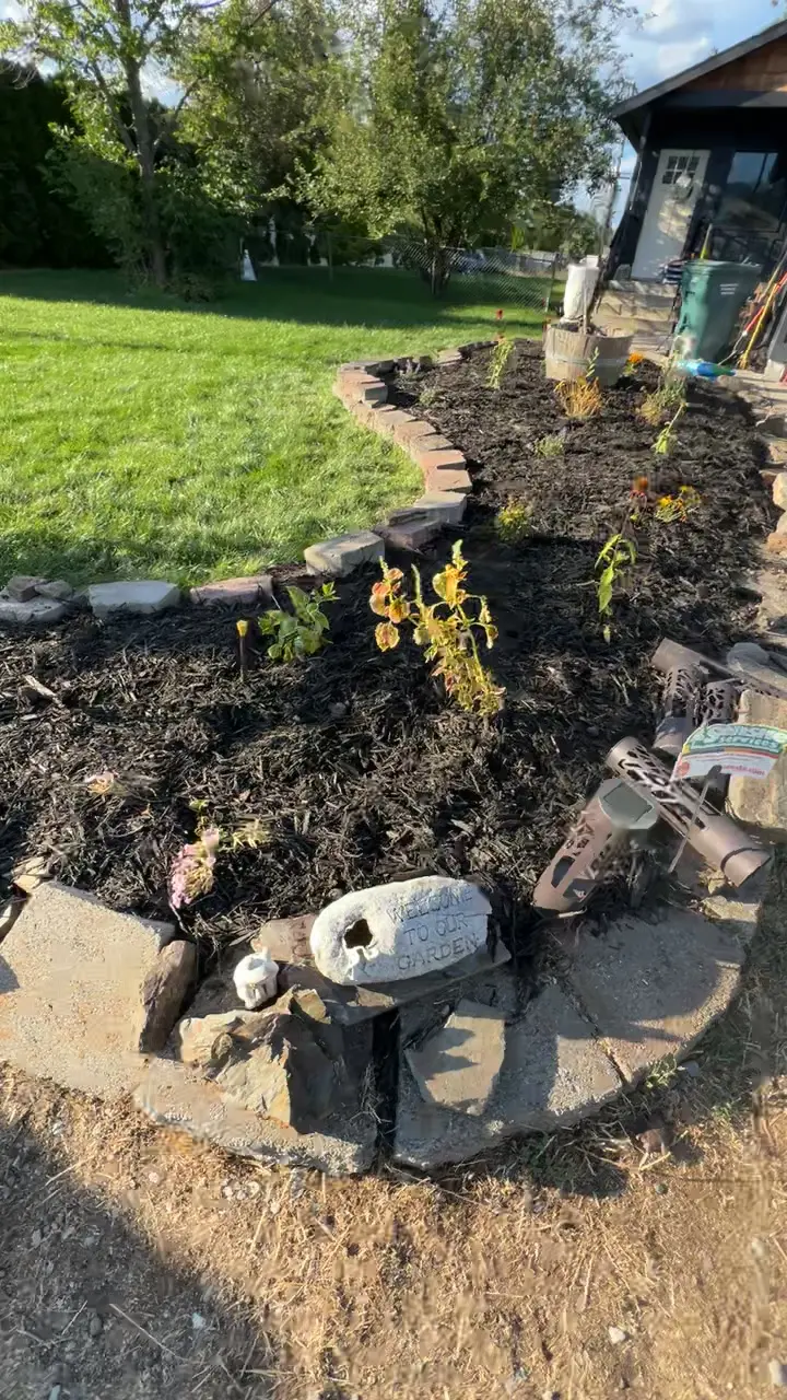 Flower bed with stone border and fresh soil next to a lawn