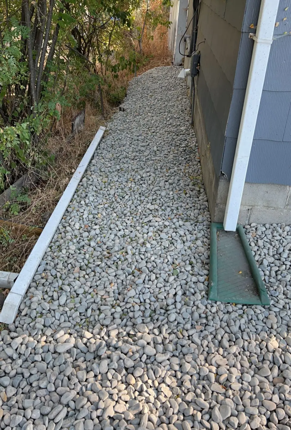 Decorative river rock installed along the side of a house